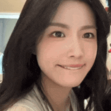 a close up of a woman 's face with long black hair smiling .