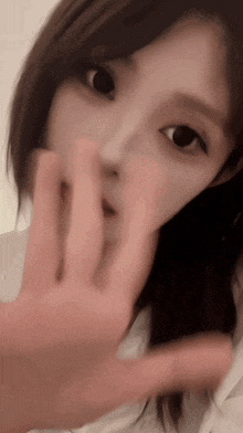 a close up of a woman 's face with a hand covering her mouth