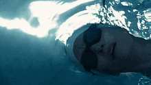 a woman wearing goggles and a swim cap is swimming in a pool