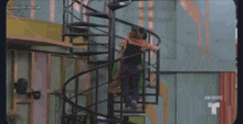 a couple standing on top of a spiral staircase with a t on the bottom
