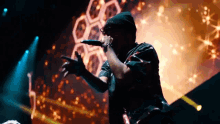 a man singing into a microphone with a honeycomb background behind him