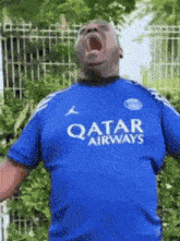 a man wearing a blue qatar airways shirt is yelling