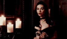 a woman in a black dress is standing next to candles .