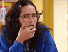 a woman wearing glasses and a blue jacket covering her mouth