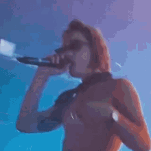 a naked woman singing into a microphone in a blue room