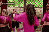 a group of women are dancing in front of a colorful stained glass window .