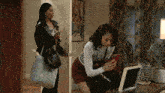 a woman is looking at her phone while another woman stands behind her