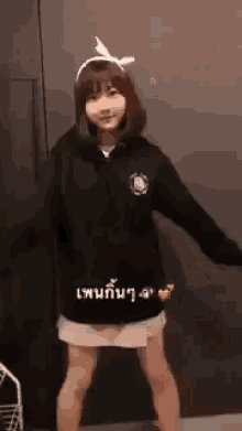 a girl wearing a black hoodie and a headband is dancing in front of a door .