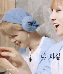 a man wearing ear muffs is smiling next to another man wearing a blue hat