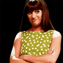 a woman in a green and white polka dot dress with her arms crossed