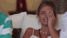 a woman is crying while sitting on a couch with her hand on her face .