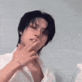 a man wearing a white shirt and a bracelet is making a peace sign .