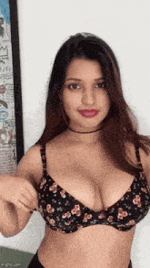 a woman in a floral bra stands in front of a framed picture