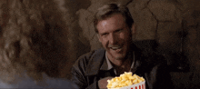 a man is holding a bucket of popcorn in front of his chest