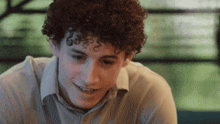 a young man with curly hair wearing a white shirt