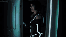 a woman in a glow in the dark costume is standing in a dark room