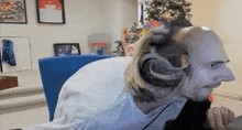 a bald man with a cat on his head is sitting in front of a computer .