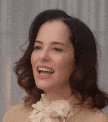 a close up of a woman 's face with a bow on her shirt