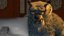 a cartoon leopard is sitting in front of a computer .
