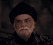 a man with a beard and mustache wearing a black turban and a black shirt .