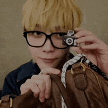 a man wearing glasses is holding a small camera that says ' oi ' on it