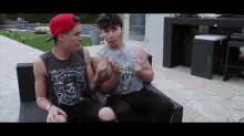 two young men are sitting on a couch and one has a shirt that says misfits
