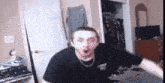 a man in a black shirt is standing in a room .