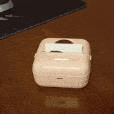 a pink box with a picture of a person on it sits on a wooden table