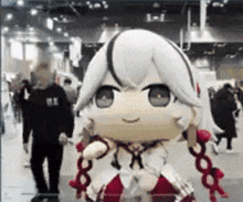 a man is standing next to a statue of a girl with white hair and red ribbons .