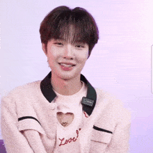 a young man wearing a pink sweater with the letter l on the front