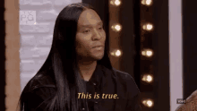 a man with long black hair is sitting in front of a wall and says `` this is true '' .