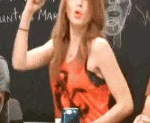 a woman in a red tank top stands in front of a blackboard with the word mar on it