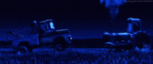 a tractor and a truck are driving down a field at night .
