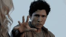 a man with curly hair reaches out towards a woman
