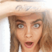 a woman with a tattoo on her wrist has a surprised look on her face ..