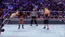 a referee stands in a wrestling ring with two wrestlers and a sign that says cross for jesus