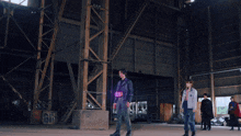 a man and a woman are standing in a warehouse with a banner hanging from the ceiling