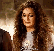 a woman with long curly hair is standing next to a man and saying oh bon , bah .