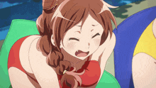 a girl in a red bikini sits on a green cushion with her eyes closed
