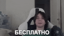a man is sitting in a white chair with the words `` бесплатно '' written on the screen .