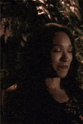 a close up of a woman making a funny face while standing in front of a tree .