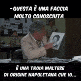 a man sitting at a desk holding a picture of a woman with the words questa e una faccia