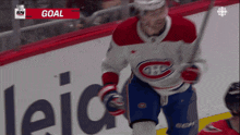 a hockey player in a red white and blue jersey with the word goal on the bottom right