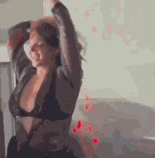 a woman in a black bra is dancing in a room with red lights behind her .