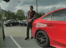 a man is standing in front of a red car with a license plate that says nc