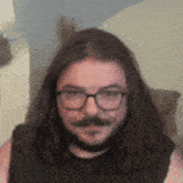 a man with long hair and glasses has a mustache .