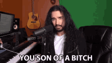 a man with long hair and a beard says you son of a bitch in front of a microphone