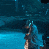 a man playing a guitar on a stage with a drum set behind him