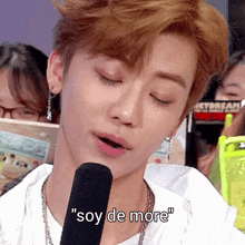 a young man speaking into a microphone with the words " soy de more " written below him