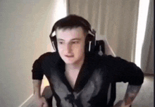 a man wearing headphones and a black shirt is sitting in a chair in a room .